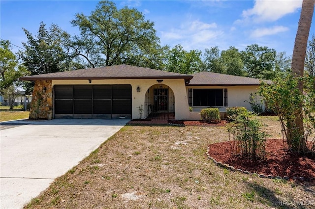ranch-style home with an attached garage, stucco siding, a front yard, and concrete driveway