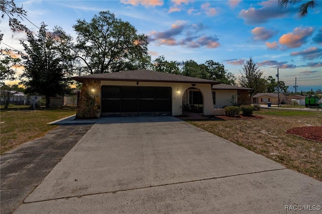 single story home with a garage, a yard, stucco siding, and driveway