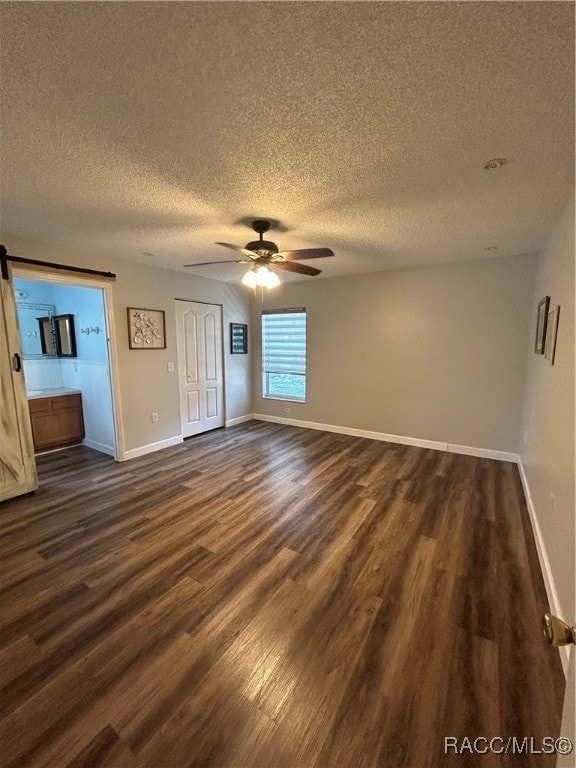 interior space with a textured ceiling, dark hardwood / wood-style floors, and ceiling fan