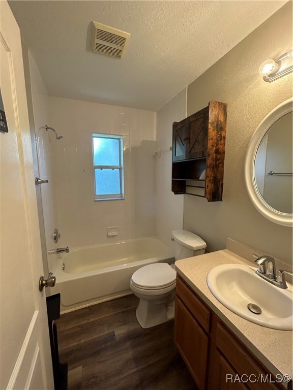 full bathroom with vanity, toilet, a textured ceiling, shower / bathtub combination, and wood-type flooring