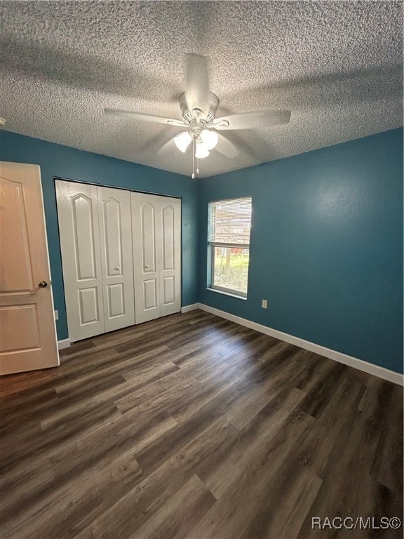 unfurnished bedroom with a closet, a textured ceiling, dark hardwood / wood-style floors, and ceiling fan