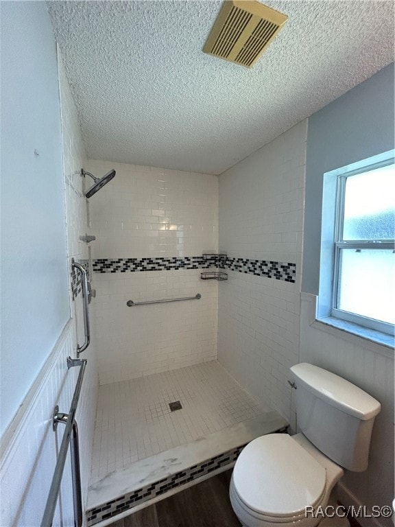 bathroom featuring tiled shower, a textured ceiling, hardwood / wood-style flooring, and toilet