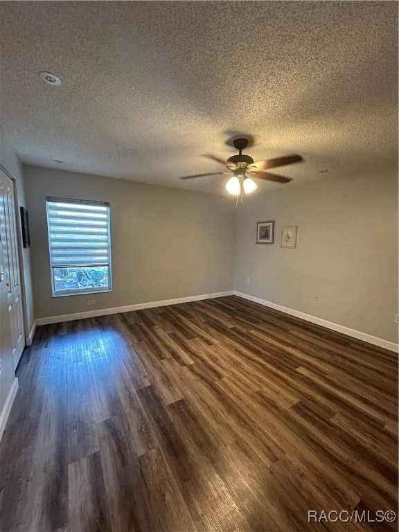 empty room with a textured ceiling, dark hardwood / wood-style floors, and ceiling fan