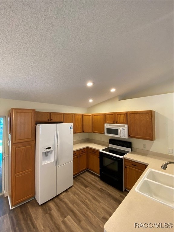 kitchen featuring a textured ceiling, white appliances, dark wood-type flooring, sink, and lofted ceiling