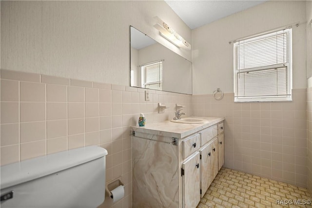 522 Hiawatha Ave, Inverness, FL 34452 - bathroom featuring tile walls, toilet, vanity, and a wainscoted wall