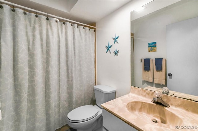 bathroom with curtained shower, vanity, and toilet