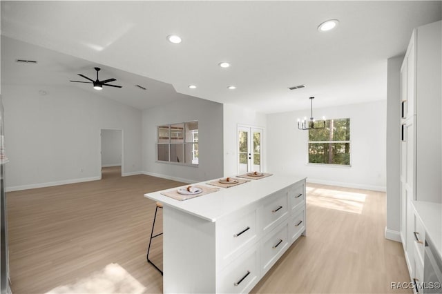 kitchen with a wealth of natural light, white cabinetry, a kitchen island, and lofted ceiling