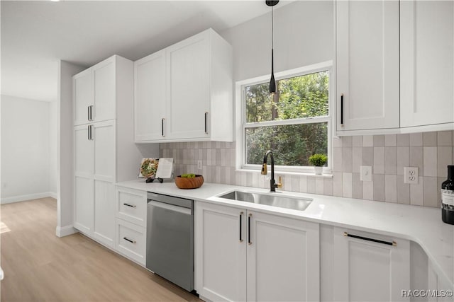 kitchen featuring decorative backsplash, stainless steel dishwasher, sink, decorative light fixtures, and white cabinets