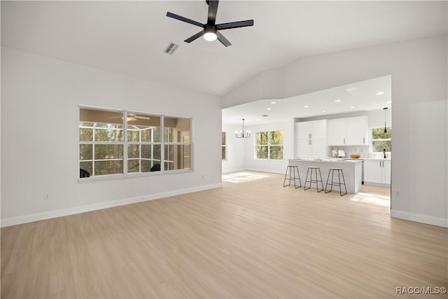 unfurnished living room featuring light hardwood / wood-style flooring, ceiling fan with notable chandelier, lofted ceiling, and sink