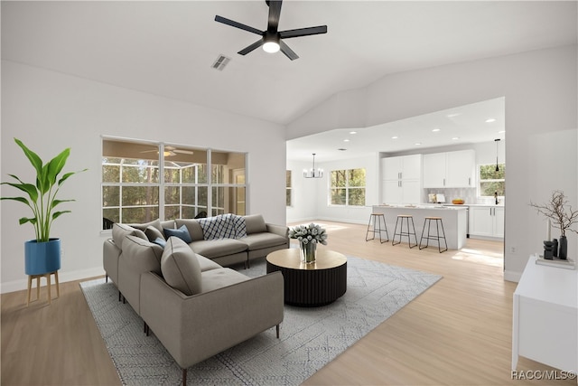 living room featuring sink, ceiling fan with notable chandelier, light hardwood / wood-style floors, and lofted ceiling