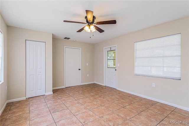 tiled spare room with ceiling fan