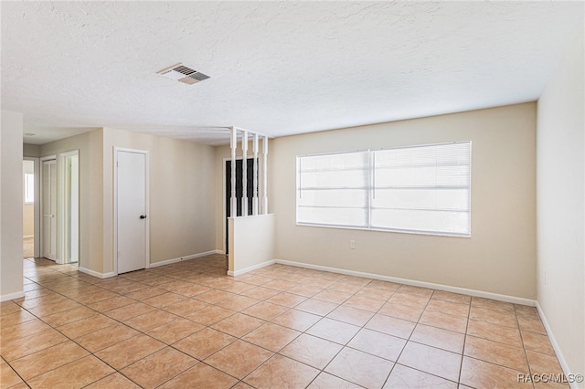 tiled spare room with a textured ceiling