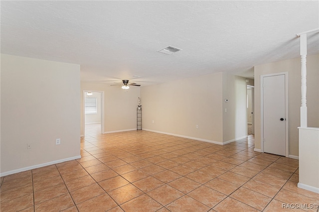 unfurnished room with ceiling fan, light tile patterned floors, and a textured ceiling