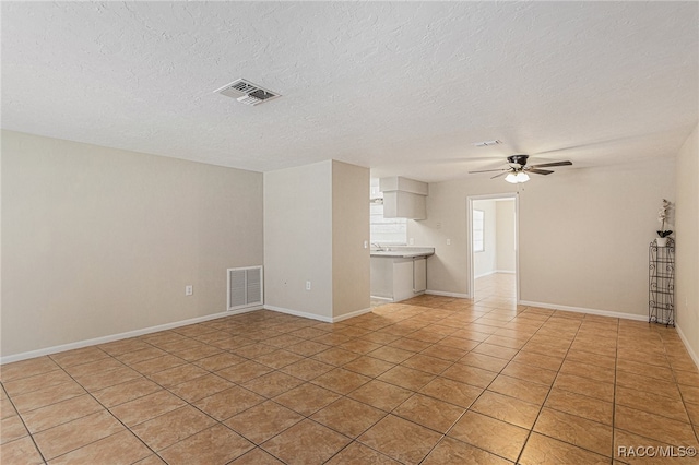 unfurnished living room with light tile patterned floors, a textured ceiling, and ceiling fan