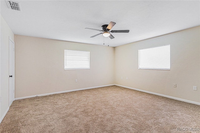 carpeted spare room with ceiling fan and plenty of natural light