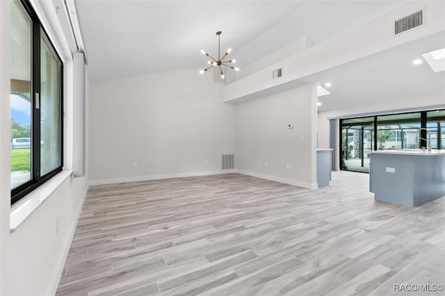 unfurnished living room with a notable chandelier and light hardwood / wood-style flooring