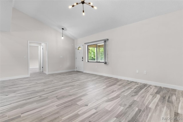 unfurnished room with an inviting chandelier, high vaulted ceiling, and light wood-type flooring