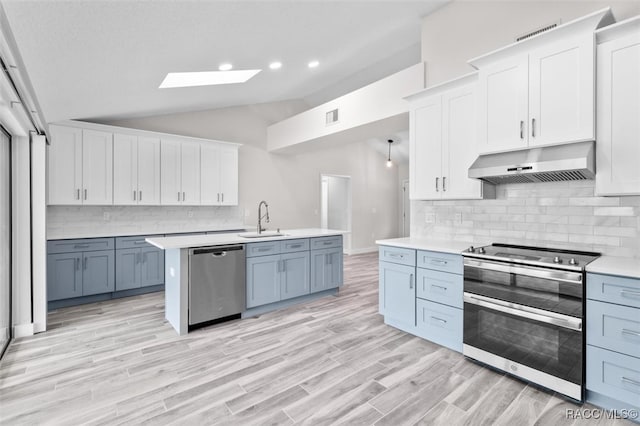 kitchen featuring stainless steel appliances, extractor fan, lofted ceiling with skylight, sink, and white cabinets