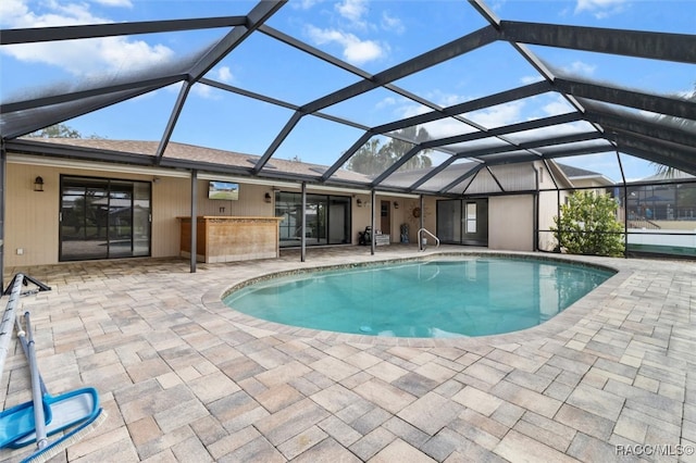 view of swimming pool featuring glass enclosure, exterior bar, and a patio