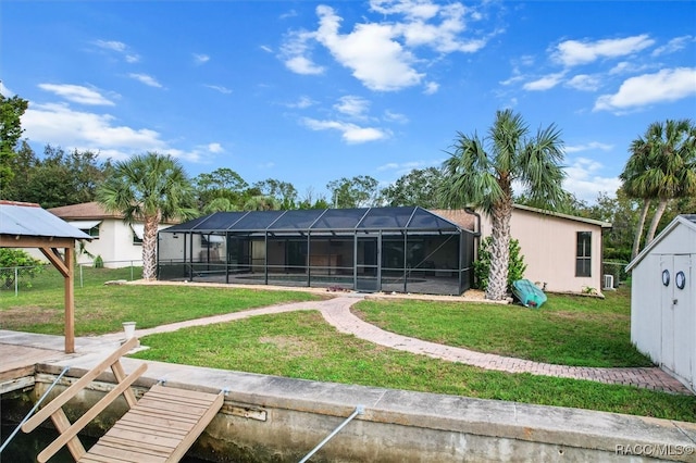 back of property featuring a lanai, a yard, and a shed