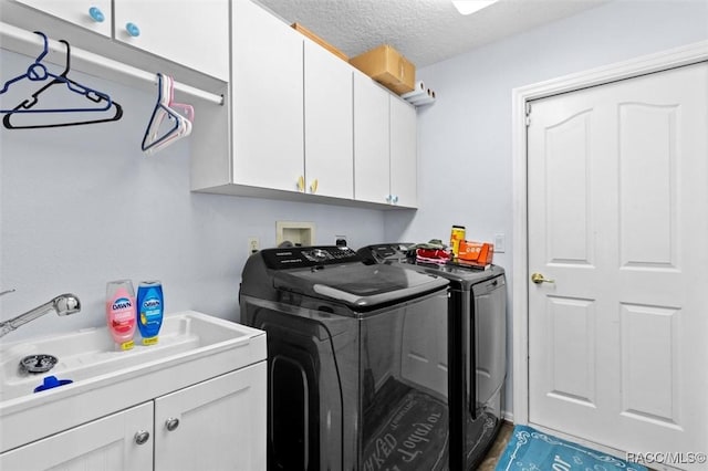 clothes washing area with a textured ceiling, separate washer and dryer, and cabinet space