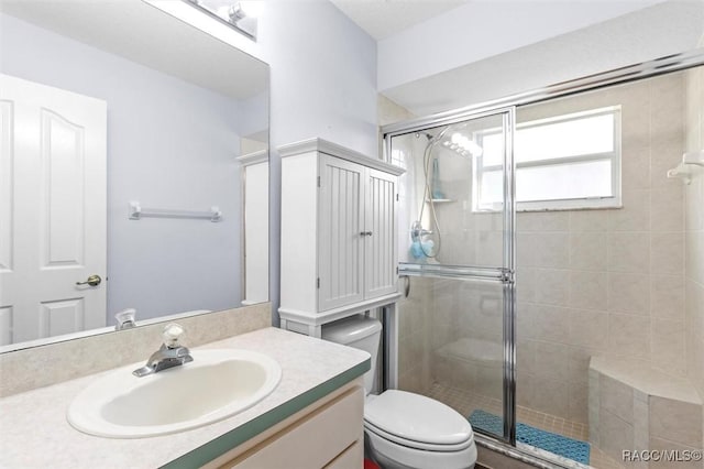 bathroom with a stall shower, vanity, and toilet