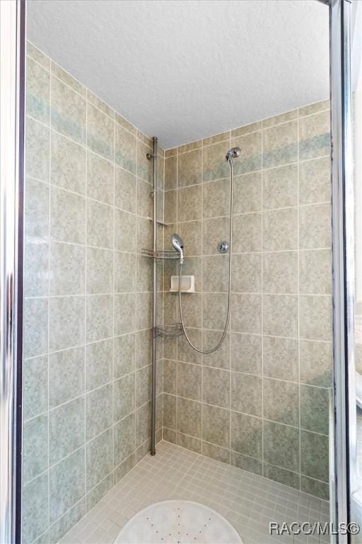 full bath with a textured ceiling and a shower stall