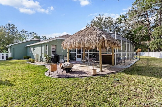 back of house featuring a fire pit, a lanai, fence, a yard, and a patio area