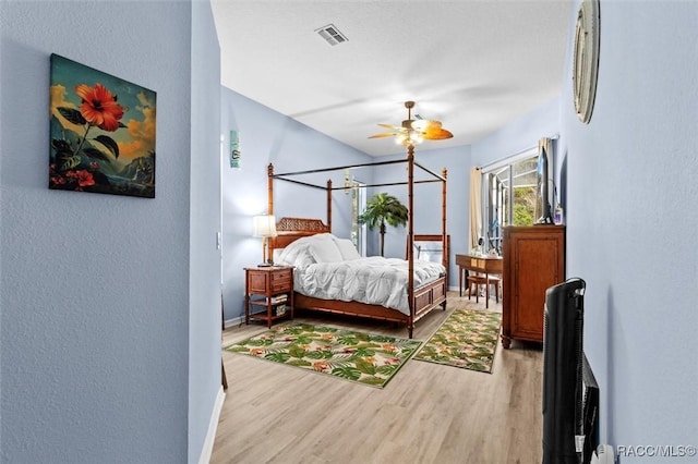 bedroom featuring a ceiling fan, visible vents, baseboards, and wood finished floors