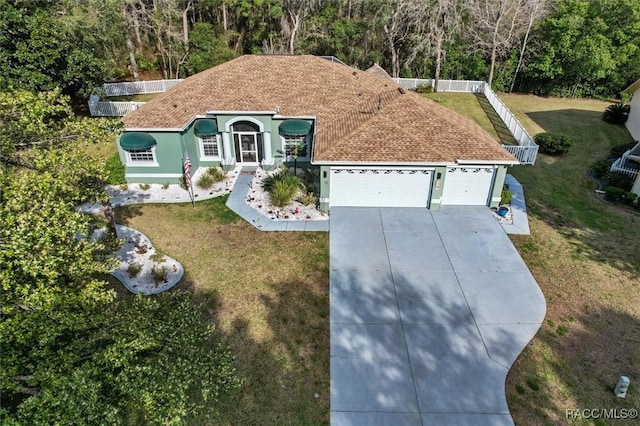 view of front of house featuring an attached garage, a shingled roof, concrete driveway, and a front yard