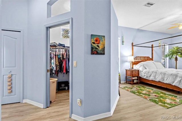 bedroom with light wood-style flooring, visible vents, a spacious closet, and baseboards