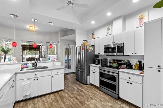 kitchen with appliances with stainless steel finishes, light countertops, a sink, and decorative backsplash