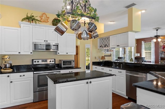 kitchen featuring white cabinets, decorative light fixtures, a center island, and stainless steel appliances