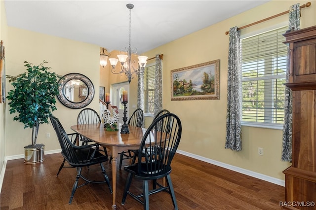 dining space with dark wood-type flooring and a notable chandelier