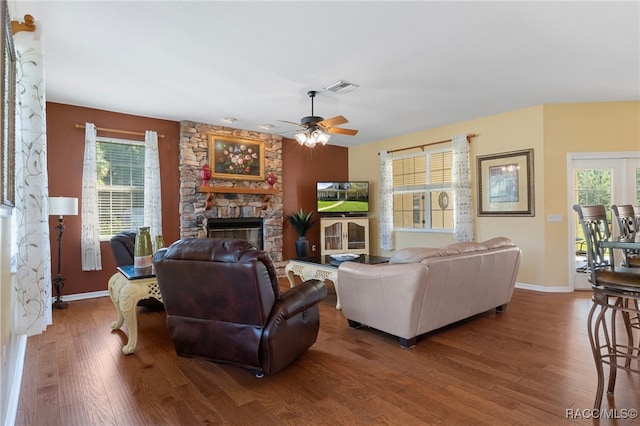 living room featuring ceiling fan, a fireplace, and wood-type flooring