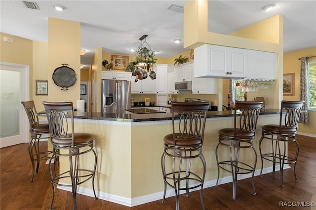 kitchen featuring a kitchen bar, appliances with stainless steel finishes, white cabinets, and dark wood-type flooring