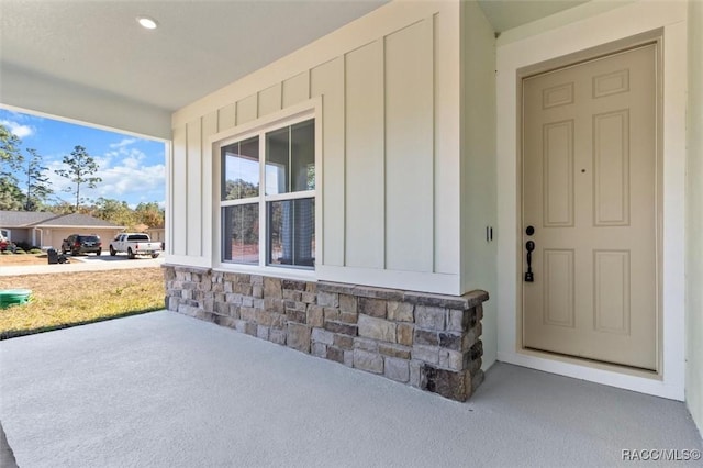 property entrance with board and batten siding and stone siding