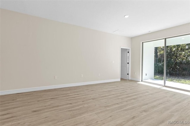 spare room featuring light wood-type flooring and baseboards