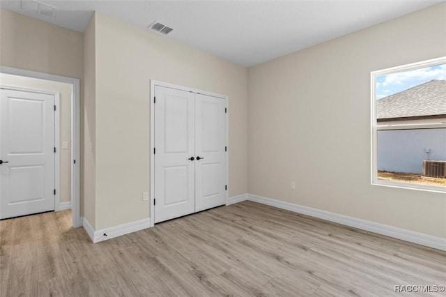 unfurnished bedroom with light wood finished floors, baseboards, visible vents, and a closet