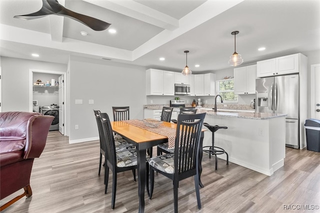 dining area with washer / clothes dryer, light hardwood / wood-style flooring, and sink