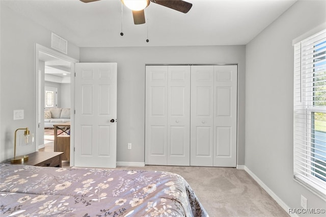 bedroom featuring ceiling fan, light carpet, and a closet