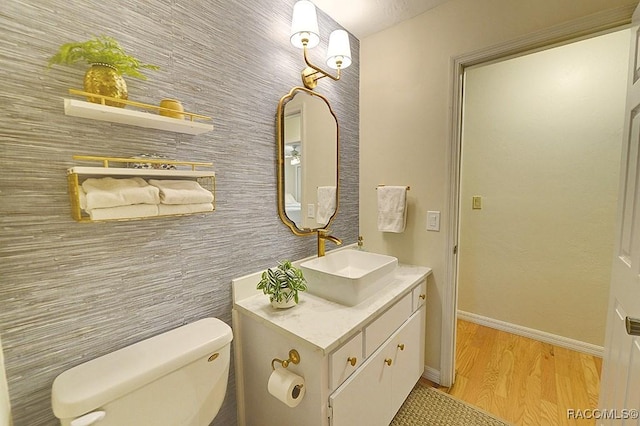 bathroom with baseboards, vanity, toilet, and wood finished floors