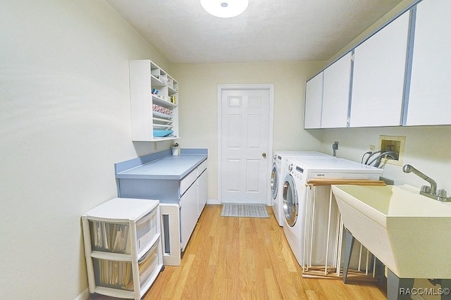 washroom featuring light wood-style flooring, a sink, baseboards, cabinet space, and washer and clothes dryer