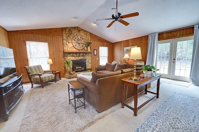 living area featuring wooden walls, light colored carpet, vaulted ceiling, french doors, and a fireplace