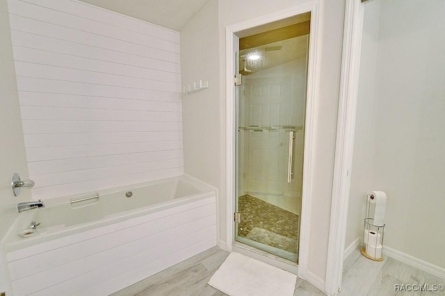 full bathroom with wood finished floors, tiled bath, a shower stall, and baseboards