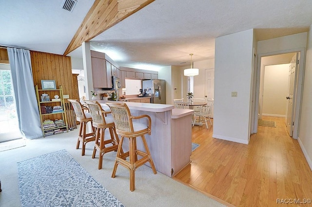 kitchen with a textured ceiling, a peninsula, visible vents, light countertops, and appliances with stainless steel finishes