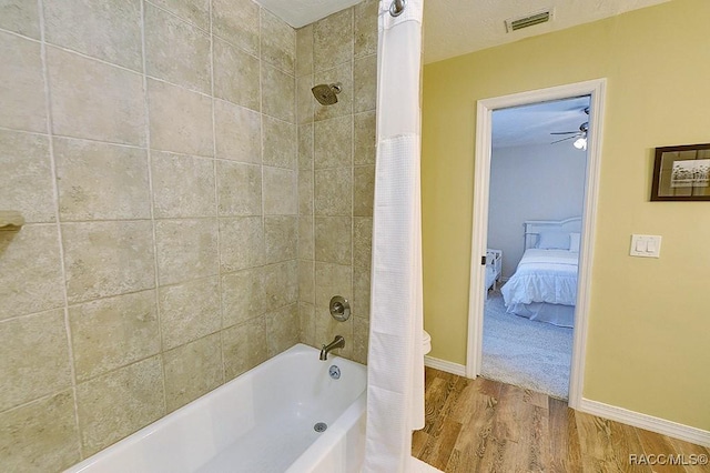 ensuite bathroom with a textured ceiling, shower / tub combo, wood finished floors, visible vents, and baseboards