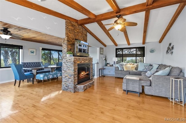 living room featuring high vaulted ceiling, a stone fireplace, light hardwood / wood-style floors, and ceiling fan