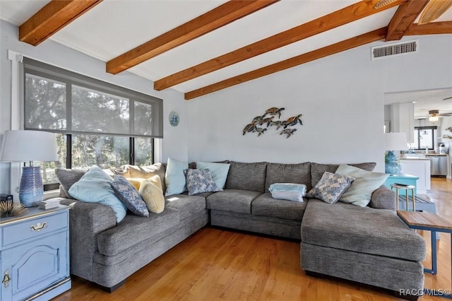 living room featuring vaulted ceiling with beams and light hardwood / wood-style flooring