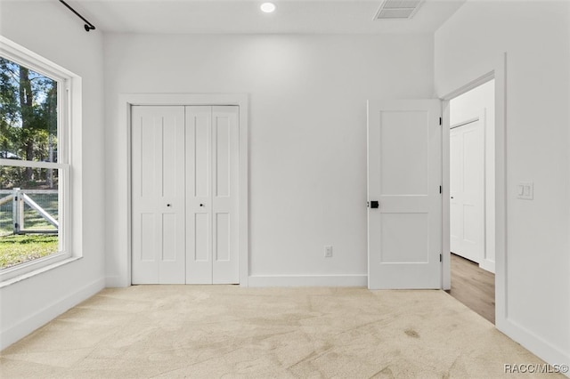 unfurnished bedroom with light carpet and a closet